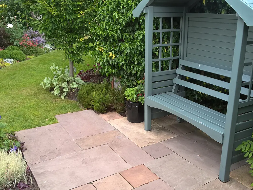 Paved patio area with garden bench and shelter